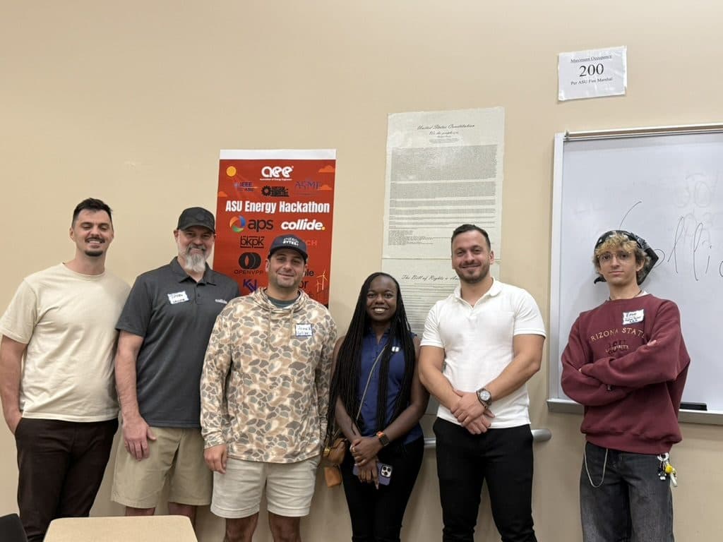Organizers and volunteers stand together in front of the ASU Energy Hackathon banner.