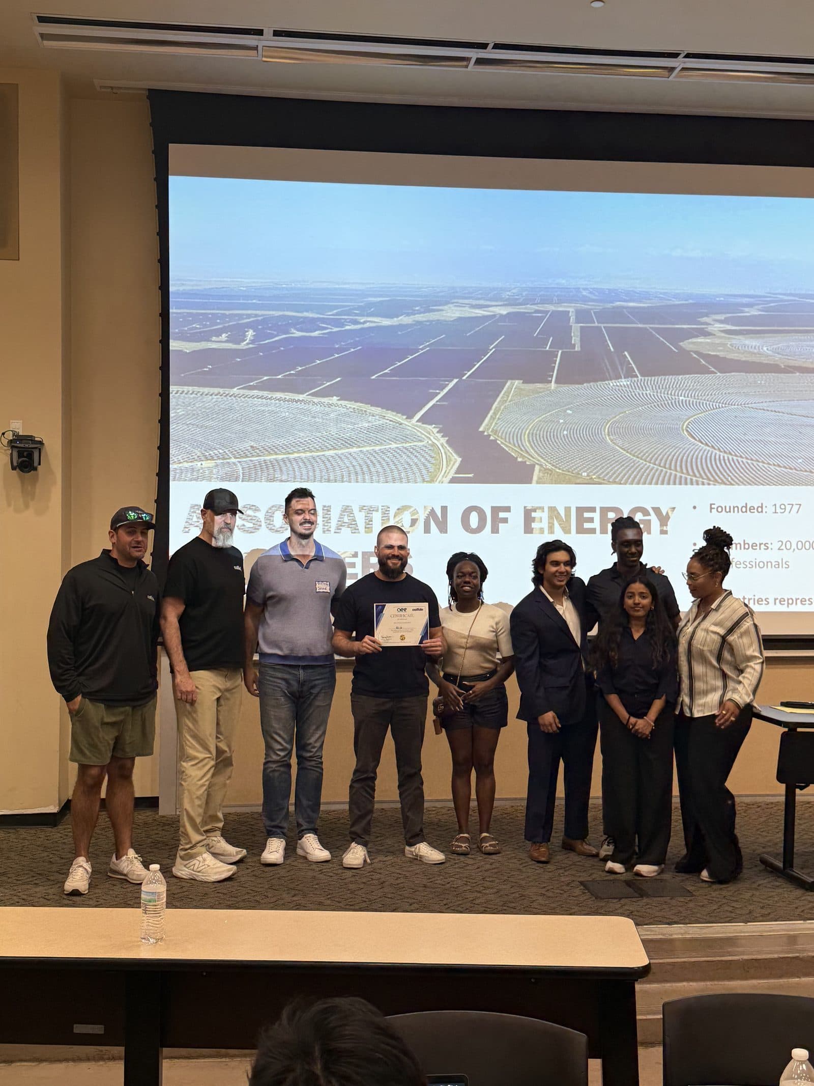 A larger team lines up across the stage holding a certificate during the awards.