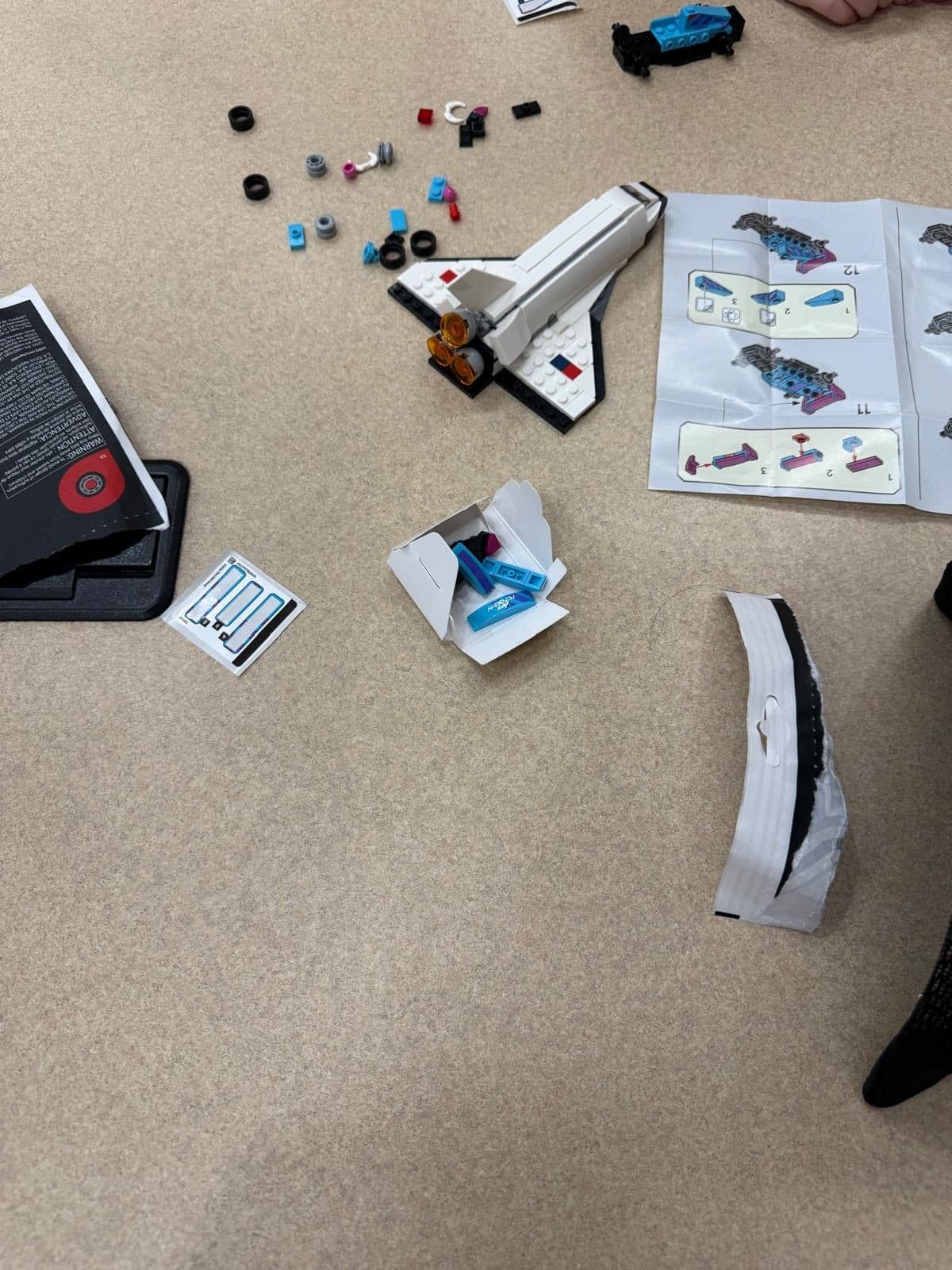 Motors, wheels, small components and assembly instructions spread across a table for the hardware track.