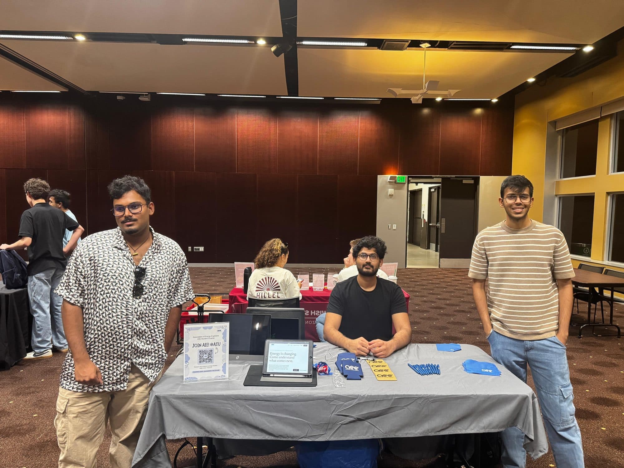 The chapter's table at Taste of the MU, with three officers behind it and chapter giveaways laid out across the front.
