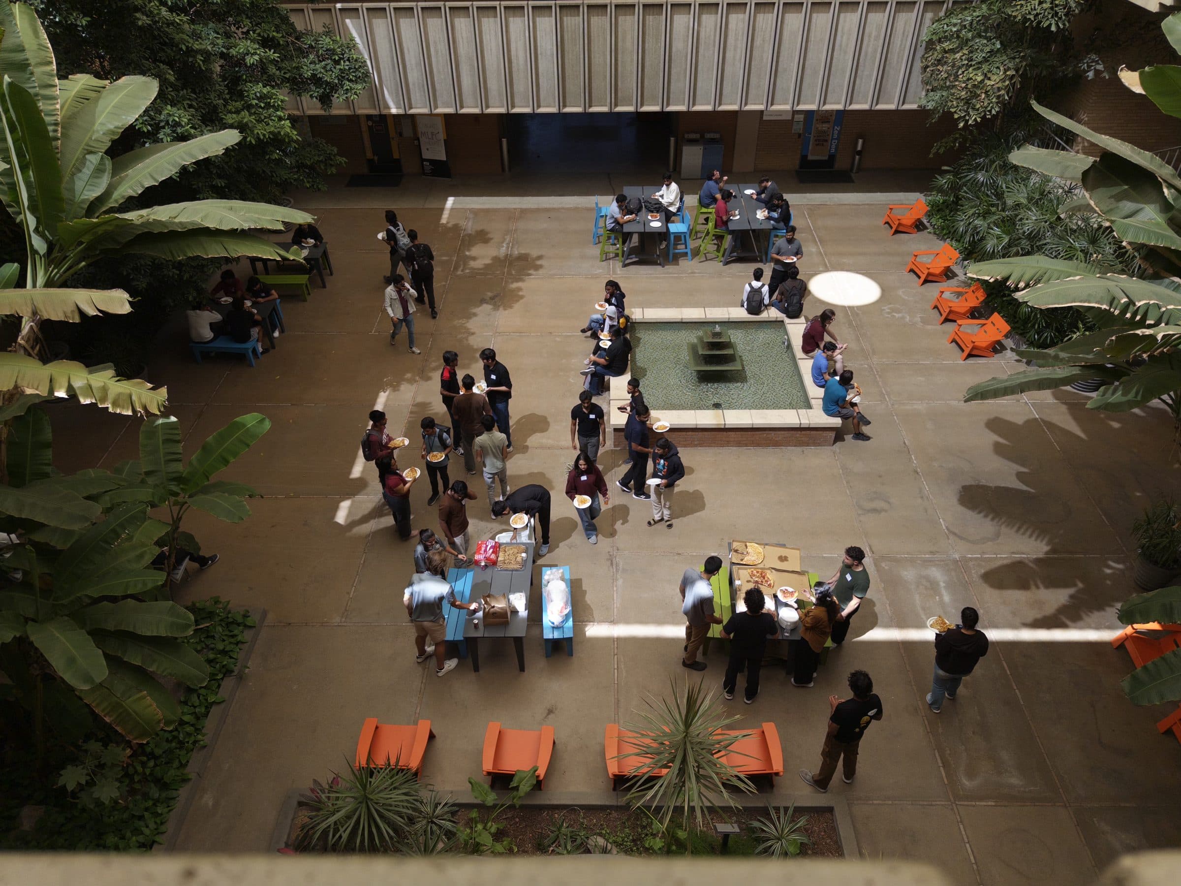 Looking down into a planted ASU courtyard where students eat lunch around a fountain and picnic tables between hackathon sessions.